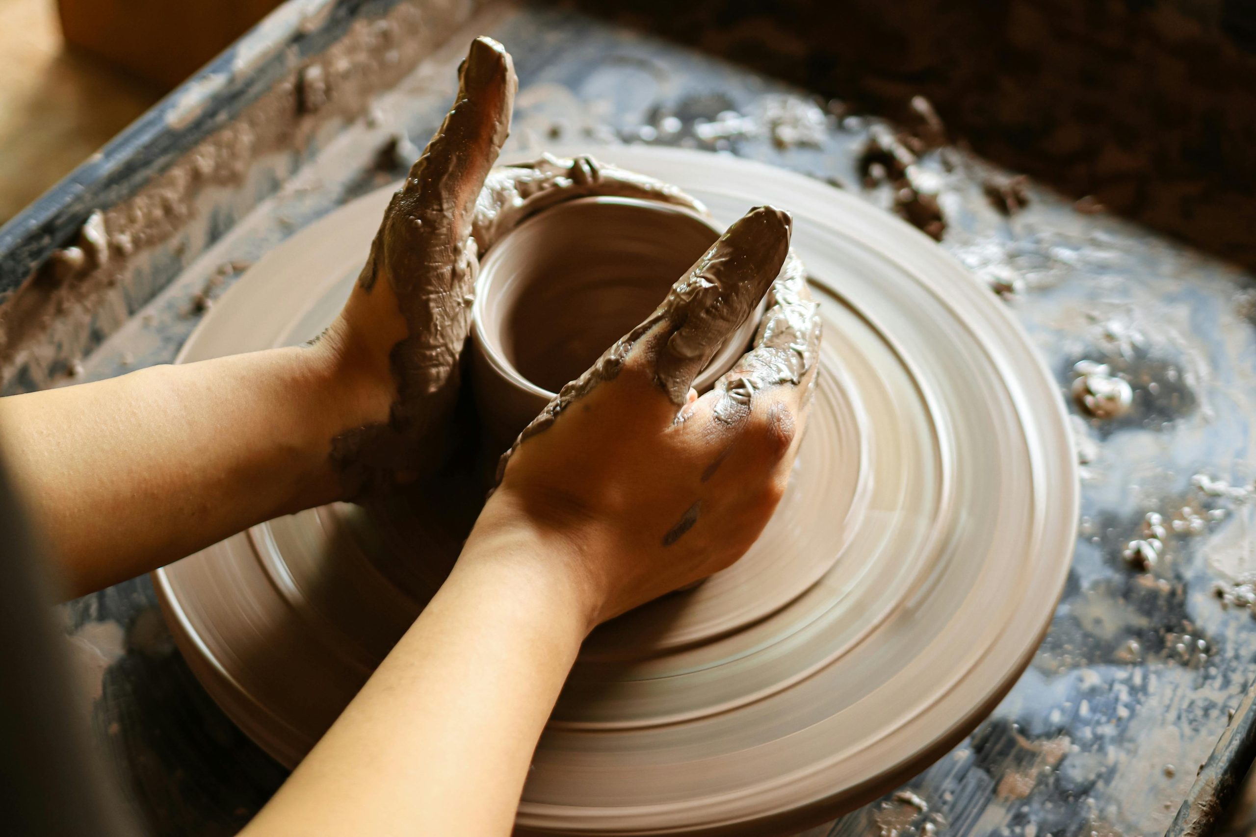 Close-up of hands crafting pottery on a wheel, showcasing skill and artistry.